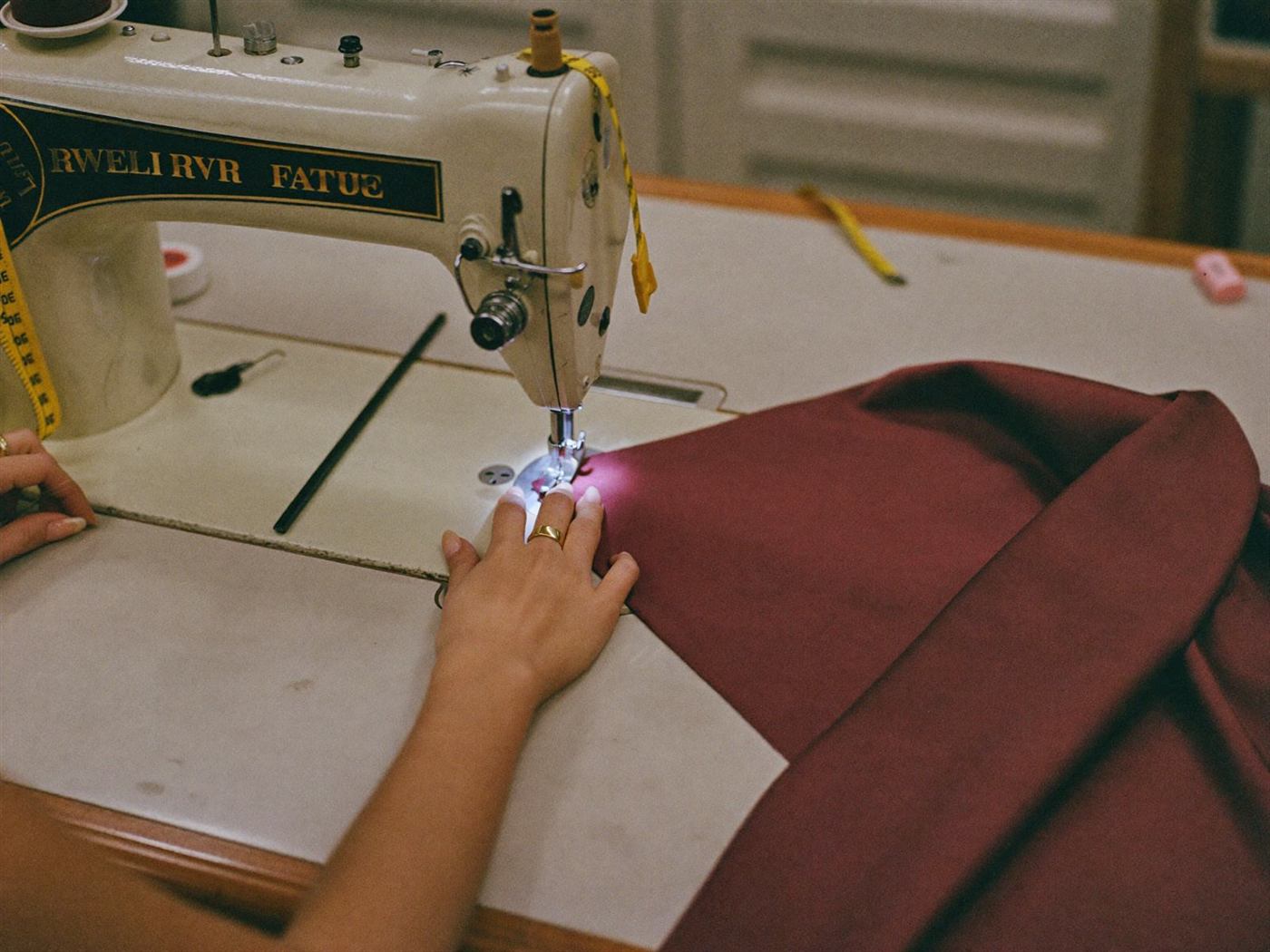 Seamstress sewing burgundy silk in the Milana atelier